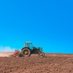 Fototapeta premium Tractor cultivating field at spring. Russian agriculture