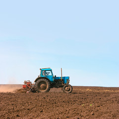 Obraz premium Tractor cultivating field at spring. Russian agriculture