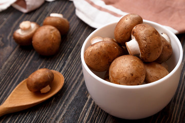 Fresh raw royal champignons in white bowl on dark wooden rustic table. Close up view