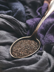 Old silver vintage spoon with chia seeds on grey and purple background. Healthy food ingredient