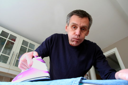 Mature man struggles with ironing the laundry