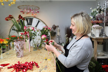 Kobieta w kwiaciarni robi bukiety z kwiatów ciętych. - obrazy, fototapety, plakaty