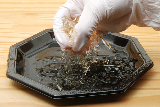 Stacked leaves of gelatine in black bowl.