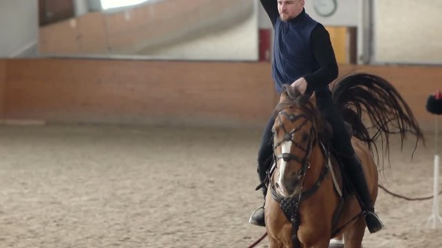Young man riding his horse and swinging his sword. A Cossack horseman cuts through a Cossack hat.