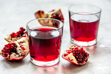 glass of pomegranate juice with fresh slices on stone background