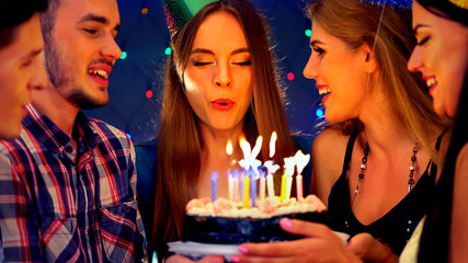Obraz na płótnie Canvas Happy friends birthday celebrating food with celebration cakes. Meet people wear in hat party blow out candles at burning candles. Two women and men have fun in nightclub.Youth celebrates together.