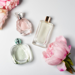 Perfume bottles with flowers on light background. Perfumery, cosmetics, fragrance collection. Flat...