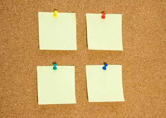 A few blank yellow stickers for taking notes on a cork board close-up.