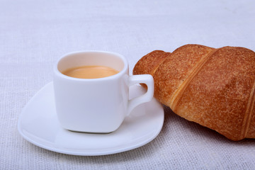 Crispy fresh croissants and cup of coffee espresso on a white background, morning breakfast, selective focus