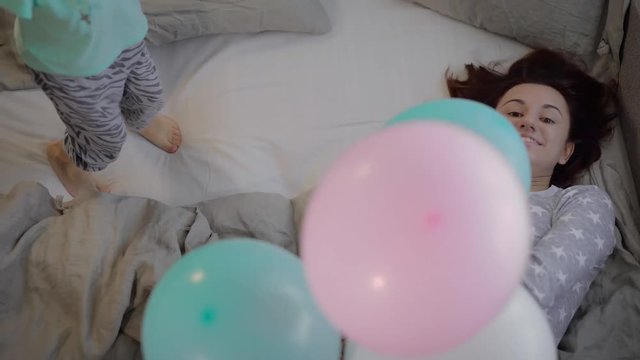 Little girl dressed in pajamas, bring your mom bunch of balloons of different colors. For a fun mom lets them up, balloons filled with helium, so fly to the ceiling