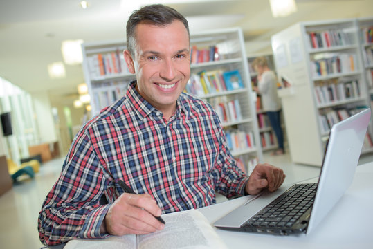 Portrait of man using a laptop in a library