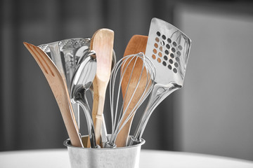 Set of metal and wooden kitchen utensils in pot on table