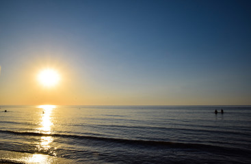 Fototapeta na wymiar Sea sunset. People bathe in the evening at sunset in the sea.