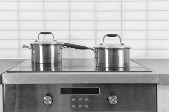 Two saucepans on electric stove in kitchen