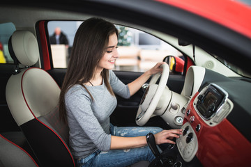 Woman driving new and modern car and turn button on dashboard panel in car