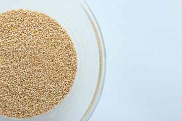 Organic quinoa seeds in glass bowl on white background