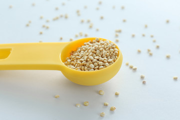 Spoon and organic quinoa seeds on white background