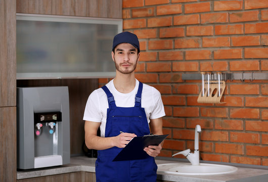 Handsome worker with pen and clipboard in kitchen