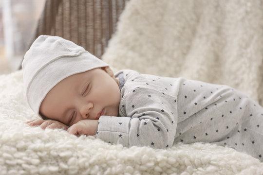 Cute little baby sleeping on plaid at home