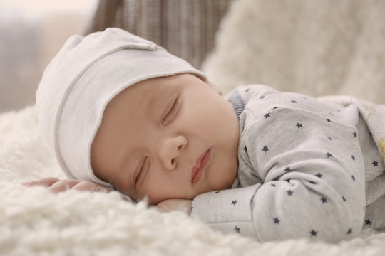 Cute little baby sleeping on plaid at home, closeup