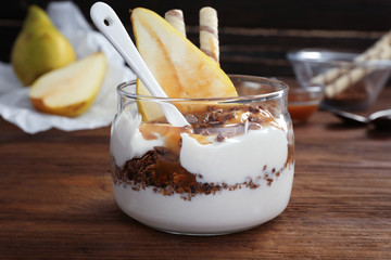 Delicious natural yogurt parfait with pear on wooden background