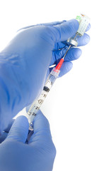 Close up of anesthesiologist's gloved hands withdrawing ondansetron, an anti nausea medicine, into a syringe with a safety needle against a white background.