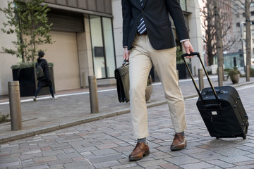 young man carrying a small case with wheels