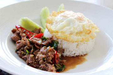 Stir fried beef with basil, chopped chili and garlic, fried egg served with steam rice