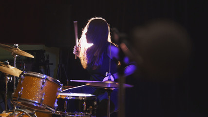 Fototapeta na wymiar Girl rock musician - female drummer performing