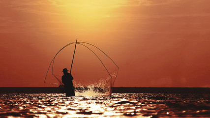 Silhouette of fishermen casting a nets into the water during Sunset,Asia,Thailand