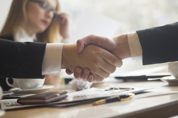 handshake business partners before signing the contract on the background of the workplace