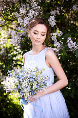 Girl with a lilac bouquet of lilac in the garden.  Lilies of the valley and forget-me-nots