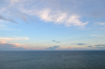 cloudy blue sky leaving for horizon above a blue surface of the sea