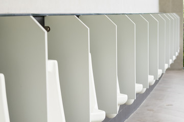 row of outdoor urinals men public toilet,Closeup white urinals in men's bathroom, design of white ceramic urinals for men,Side view