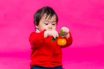 Cute chinese baby holding a tangerine