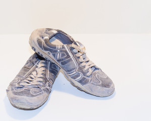 very old running shoes with laces on a light background.