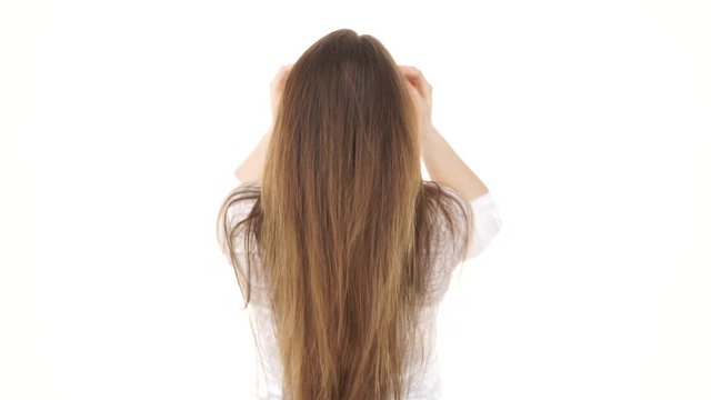 Young woman shaking combing with fingers her healthy hair. Rear view of the young female with beauty straight long brown hairs, studio shot isolated on white background 4K ProRes HQ codec