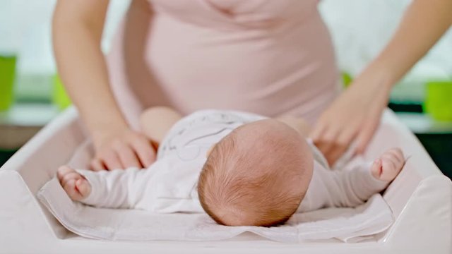 Mom changes the diaper of a small baby girl