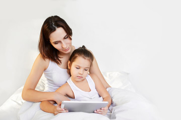 mom and little daughter reading tablet and smile