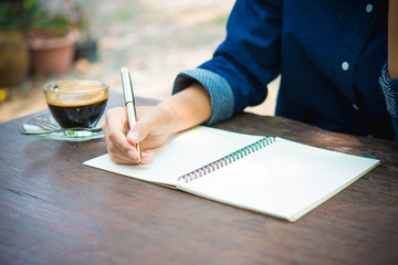 women writing and key board coffee on wooden table..