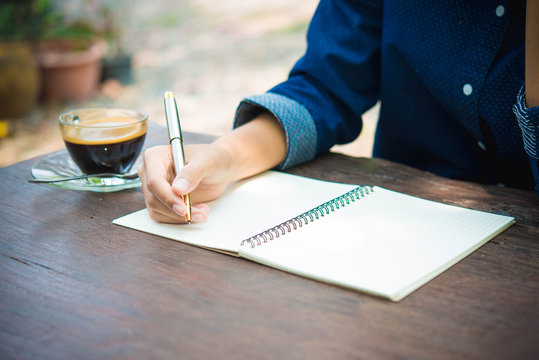 women writing and key board coffee on wooden table..