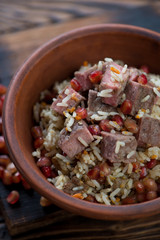 Close-up of pilaf with beef meat and pomegranate seeds served in ceramic bowl