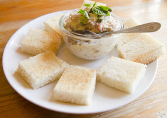 Tuna fish sandwich with tomatoes, lettuce and mayonnaise on a wooden board