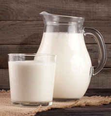 jug and glass of milk on a wooden background