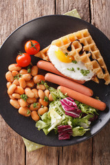 Healthy breakfast: waffle sandwich with egg, sausages, beans and salad close-up. Vertical top view