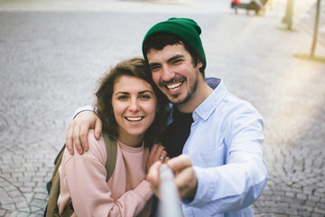 Obraz premium A loving couple is doing a selfie with selfie stick on a city street