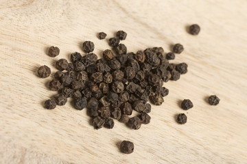 black pepper in white spoon on wooden background