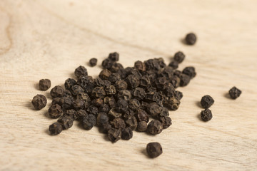 black pepper in white spoon on wooden background