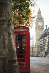 Fototapeta na wymiar Close-up view of an old red telephone box, blurred big ben and house of parliament in the background, London, United Kingdom.