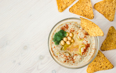 A bowl of creamy hummus with olive oil and chips.